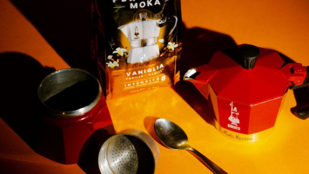 a can of coffee next to a cup and spoon