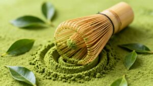Premium Yame matcha powder with bamboo whisk and tea leaves.