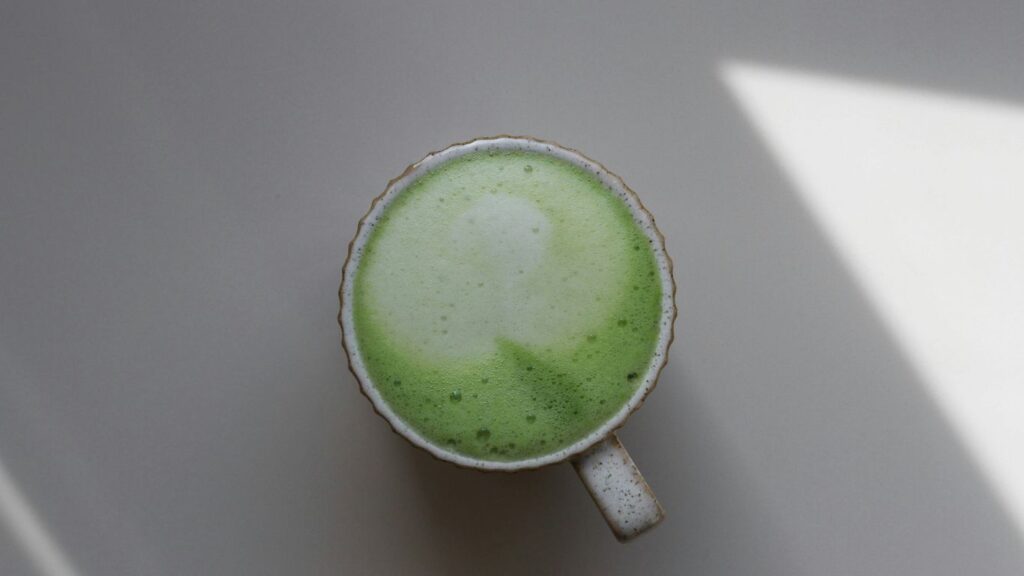 a cup of green liquid sitting on top of a table